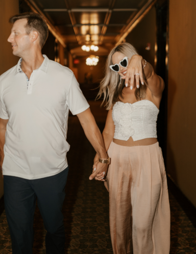 Couple walking down the hallway and bride flashing her ring