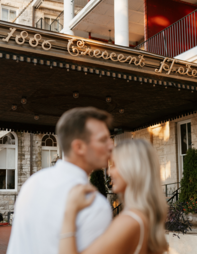 Man kissing woman's forehead in front of the 1886 Crescent Hotel awning